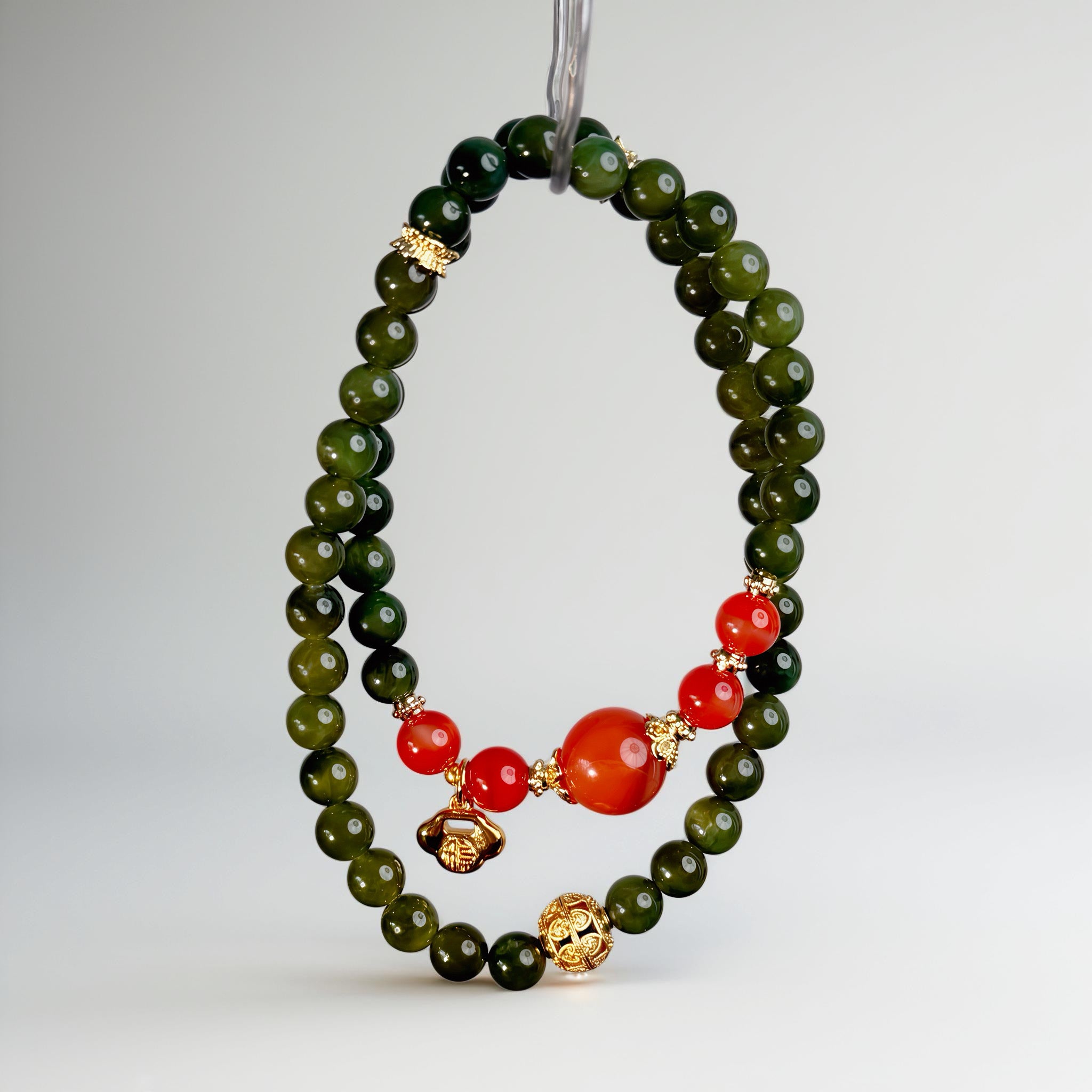 Handcrafted deep green gemstone bracelet with red accents and symbolic gold lock detail, embodying grounding, protection, and refined energy boundaries.